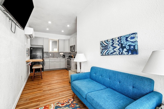 1200 E Walnut St, Springfield, MO 65802 - living area featuring recessed lighting, light wood-style floors, a wall mounted air conditioner, a textured wall, and baseboards