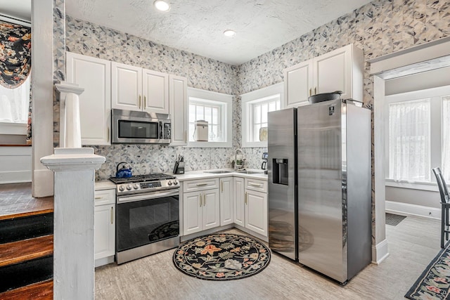 1200 E Walnut St, Springfield, MO 65802 - kitchen with appliances with stainless steel finishes, a sink, light countertops, light wood-type flooring, and wallpapered walls