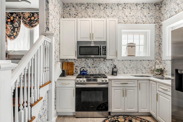 1200 E Walnut St, Springfield, MO 65802 - kitchen with stainless steel appliances, a sink, wallpapered walls, light countertops, and healthy amount of natural light