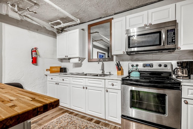 1200 E Walnut St, Springfield, MO 65802 - kitchen with appliances with stainless steel finishes, a sink, light countertops, white cabinetry, and backsplash