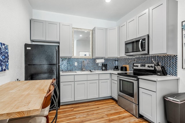 1200 E Walnut St, Springfield, MO 65802 - kitchen with appliances with stainless steel finishes, a sink, light countertops, backsplash, and light wood-style flooring