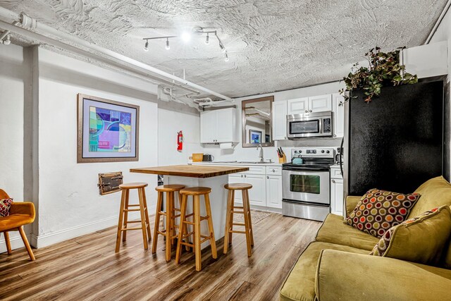 1200 E Walnut St, Springfield, MO 65802 - kitchen featuring stainless steel appliances, wooden counters, a sink, light wood-type flooring, and a breakfast bar area