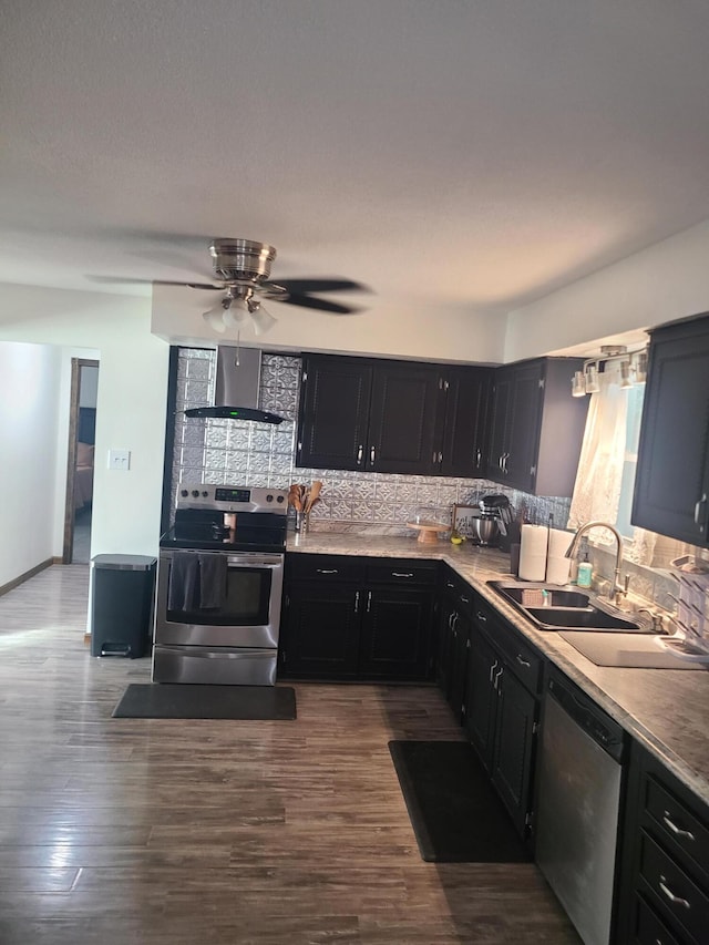 511 3rd St, Mccune, MO 66753 - kitchen with appliances with stainless steel finishes, wall chimney range hood, a sink, dark cabinetry, and tasteful backsplash