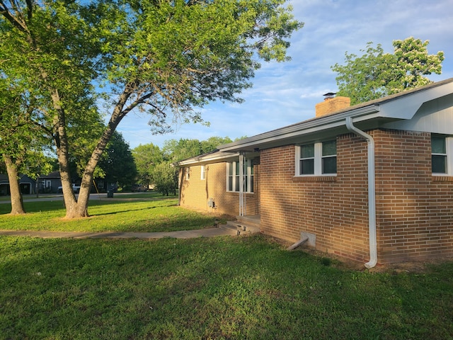 511 3rd St, Mccune, MO 66753 - view of property exterior featuring a chimney, a lawn, and brick siding
