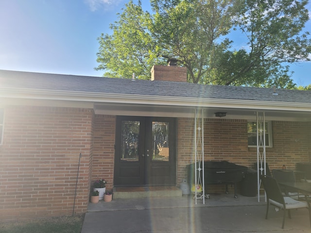 511 3rd St, Mccune, MO 66753 - property entrance with french doors, brick siding, a chimney, and a patio area