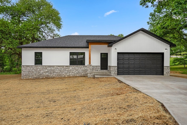 806 Iris Ave, Crane, MO 65633 - view of front of house with stone siding, an attached garage, driveway, and roof with shingles