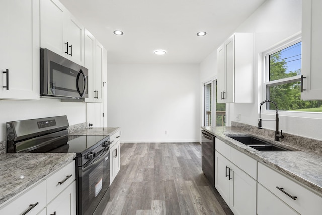806 Iris Ave, Crane, MO 65633 - kitchen with stainless steel appliances, a sink, wood finished floors, white cabinets, and light stone countertops