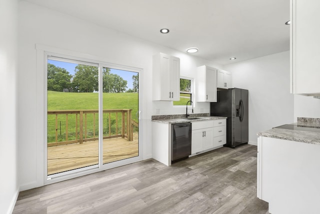 806 Iris Ave, Crane, MO 65633 - kitchen with black dishwasher, stainless steel fridge, white cabinets, light wood-type flooring, and baseboards
