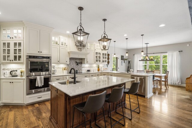 4936 S Butterfield Pl, Brookline, MO 65619 - kitchen with appliances with stainless steel finishes, a peninsula, a sink, tasteful backsplash, and dark wood-type flooring