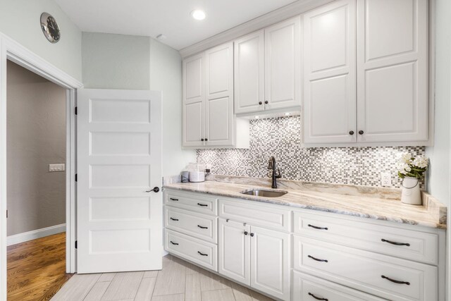 4936 S Butterfield Pl, Brookline, MO 65619 - kitchen featuring a sink, tasteful backsplash, light stone counters, white cabinets, and baseboards