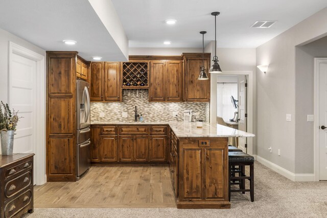 4936 S Butterfield Pl, Brookline, MO 65619 - kitchen featuring stainless steel fridge with ice dispenser, a peninsula, a kitchen bar, tasteful backsplash, and a sink