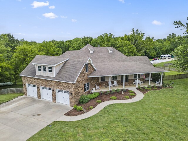 4936 S Butterfield Pl, Brookline, MO 65619 - view of front of home featuring stone siding, concrete driveway, covered porch, roof with shingles, and a view of trees