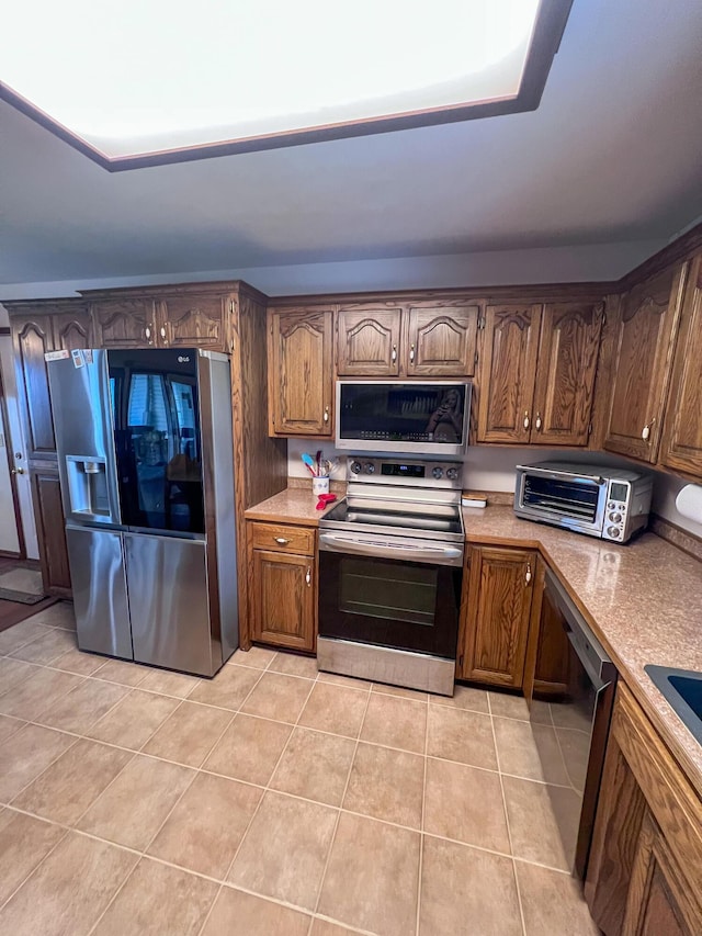 21650 Kings Loop, Hermitage, MO 65668 - kitchen with appliances with stainless steel finishes, light tile patterned floors, light countertops, and brown cabinetry