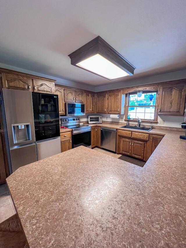 21650 Kings Loop, Hermitage, MO 65668 - kitchen featuring appliances with stainless steel finishes, a sink, a peninsula, light countertops, and brown cabinets