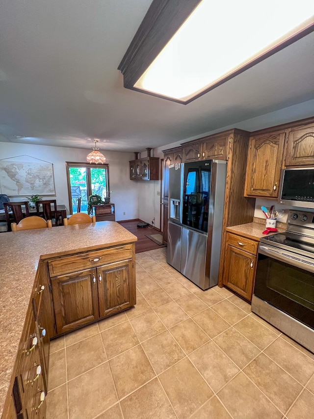 21650 Kings Loop, Hermitage, MO 65668 - kitchen with stainless steel appliances, light tile patterned flooring, light countertops, a chandelier, and brown cabinets