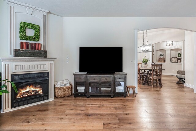 1086 S Joshua Ave, Republic, MO 65738 - living room featuring arched walkways, wood finished floors, a warm lit fireplace, crown molding, and baseboards