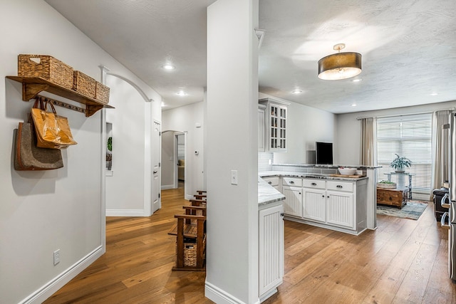 1086 S Joshua Ave, Republic, MO 65738 - kitchen with light wood-type flooring, a peninsula, glass insert cabinets, white cabinetry, and baseboards