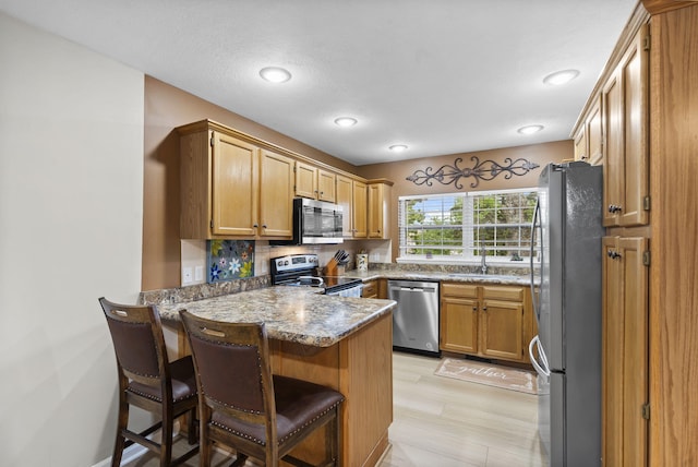 650 S Woodbridge Ct, Nixa, MO 65714 - kitchen featuring stainless steel appliances, a peninsula, a sink, tasteful backsplash, and light stone counters