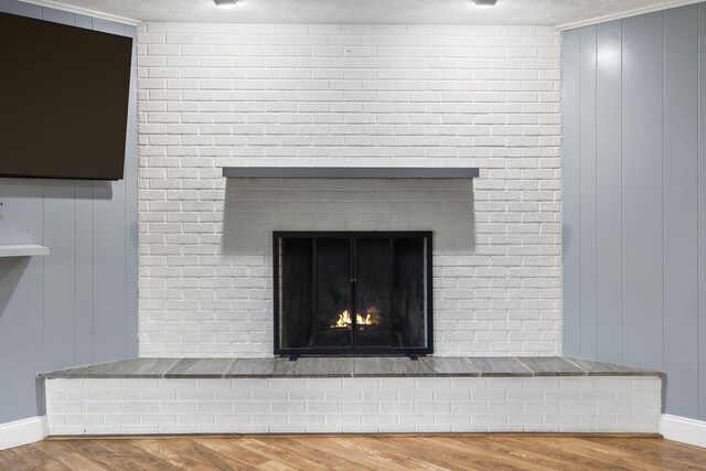 1514 W Swan St, Springfield, MO 65807 - detailed view of a fireplace, wood finished floors, baseboards, a textured ceiling, and wooden walls