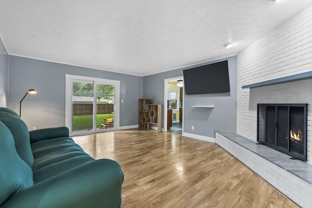 1514 W Swan St, Springfield, MO 65807 - living area with wood finished floors, a brick fireplace, a textured ceiling, ceiling fan, and baseboards