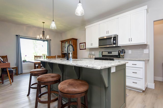1503 W Ragweed Ct, Ozark, MO 65721 - kitchen with stainless steel appliances, a sink, light wood-style floors, a chandelier, and backsplash