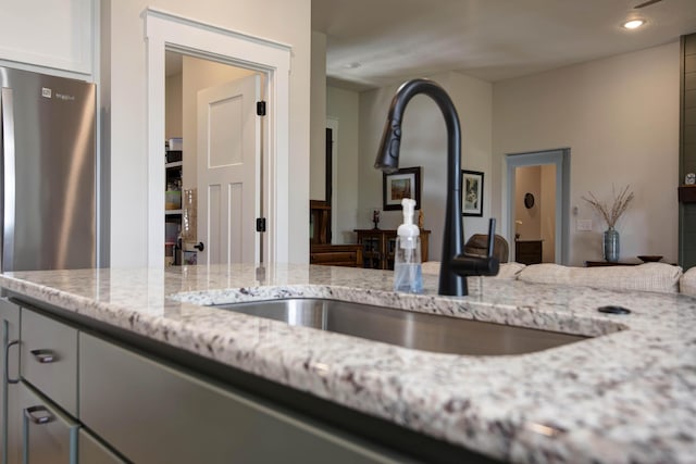 1503 W Ragweed Ct, Ozark, MO 65721 - kitchen view of a sink, light stone counters, freestanding refrigerator, recessed lighting, and white cabinets