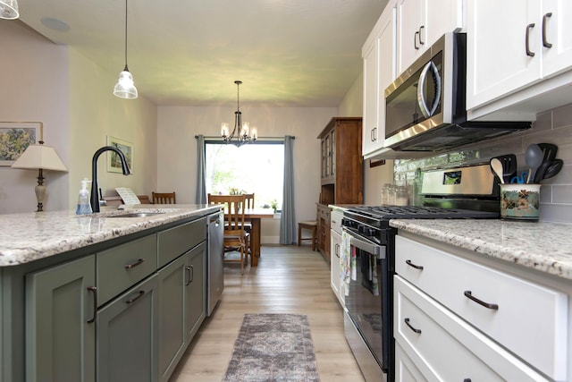 1503 W Ragweed Ct, Ozark, MO 65721 - kitchen featuring stainless steel appliances, a sink, white cabinets, light wood-style floors, and a chandelier
