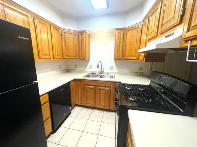 607 Robin Rd, Mountain Grove, MO 65711 - kitchen with black appliances, under cabinet range hood, a sink, light tile patterned floors, and brown cabinets