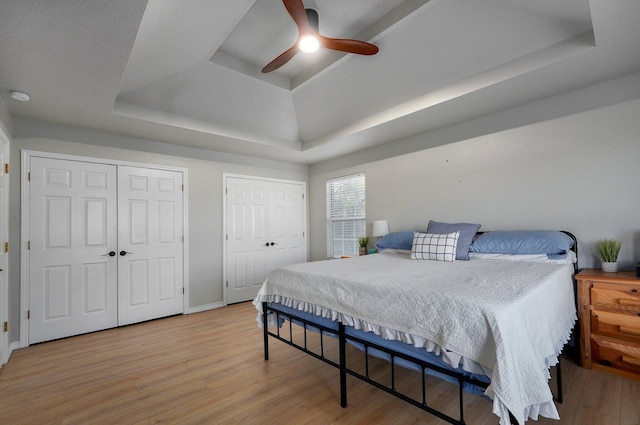 505 Thunderbird Dr, Rogersville, MO 65742 - bedroom with a tray ceiling, multiple closets, light wood-style floors, baseboards, and a ceiling fan
