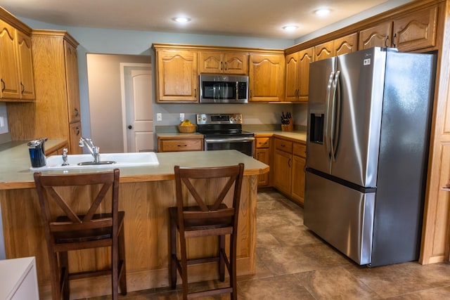 711 Morning Glory Dr, Nixa, MO 65714 - kitchen with stainless steel appliances, a peninsula, brown cabinetry, light countertops, and recessed lighting