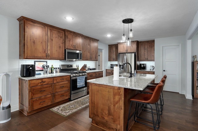 1002 E Tipperary Ct, Nixa, MO 65714 - kitchen featuring appliances with stainless steel finishes, decorative backsplash, dark wood-style floors, a center island with sink, and recessed lighting