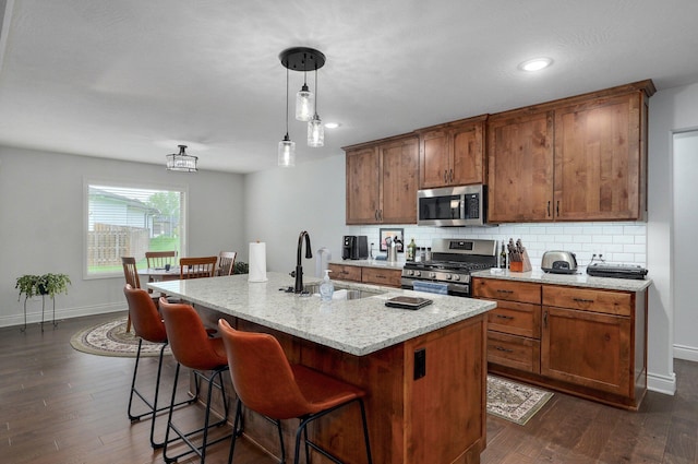 1002 E Tipperary Ct, Nixa, MO 65714 - kitchen featuring stainless steel appliances, decorative backsplash, a kitchen bar, dark wood-style floors, and hanging light fixtures