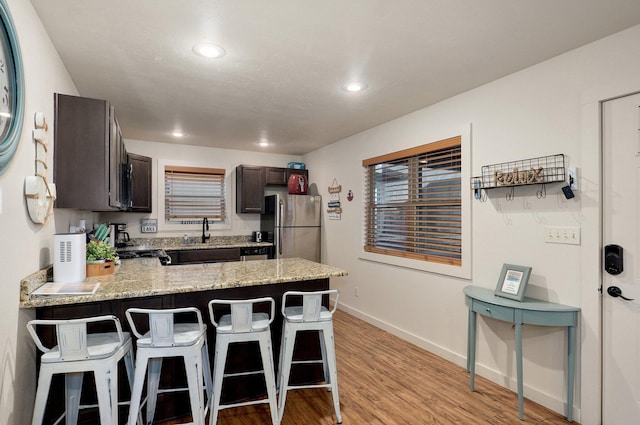 4656 W State Highway H Unit 3, Lampe, MO 65681 - kitchen featuring freestanding refrigerator, a peninsula, dark brown cabinets, a kitchen bar, and light stone counters