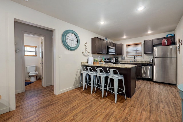 4656 W State Highway H Unit 3, Lampe, MO 65681 - kitchen featuring stainless steel appliances, dark brown cabinets, a peninsula, a kitchen bar, and wood finished floors