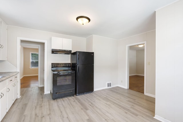 1116 W University St, Springfield, MO 65807 - kitchen with black appliances, under cabinet range hood, light wood-style flooring, and white cabinetry