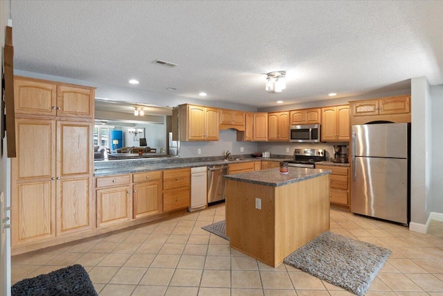 783 Winn Rd Unit 5B, Osage Beach, MO 65065 - kitchen with stainless steel appliances, dark countertops, a center island, light tile patterned floors, and a textured ceiling
