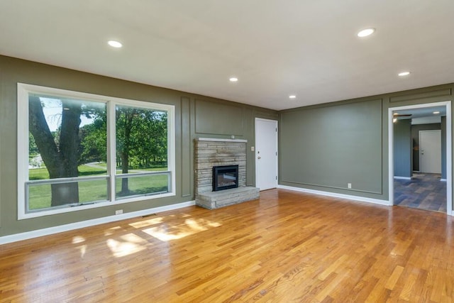 1318 S Farm Rd Unit 205, Springfield, MO 65809 - unfurnished living room featuring light wood-style flooring, recessed lighting, baseboards, a stone fireplace, and a decorative wall