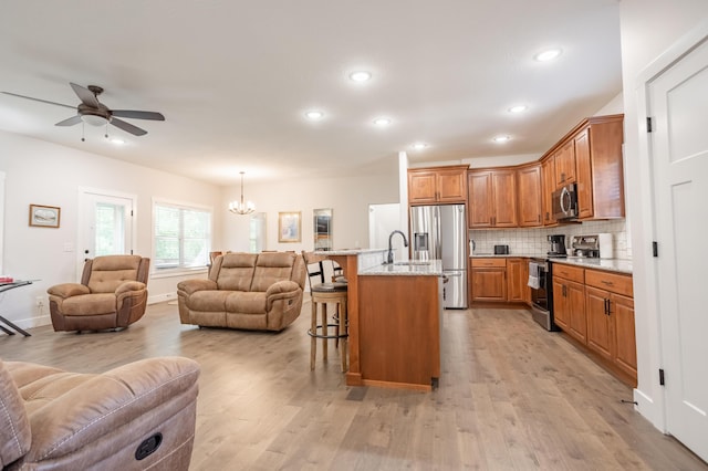 4738 N Florence Ave, Ozark, MO 65721 - kitchen featuring appliances with stainless steel finishes, open floor plan, a kitchen breakfast bar, light wood finished floors, and a chandelier