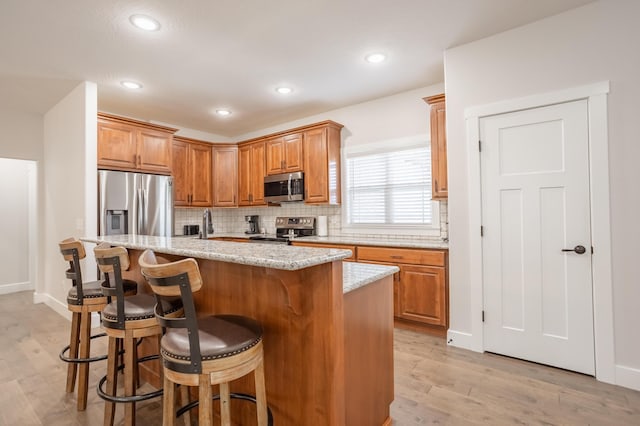 4738 N Florence Ave, Ozark, MO 65721 - kitchen featuring appliances with stainless steel finishes, decorative backsplash, light wood finished floors, a kitchen bar, and recessed lighting