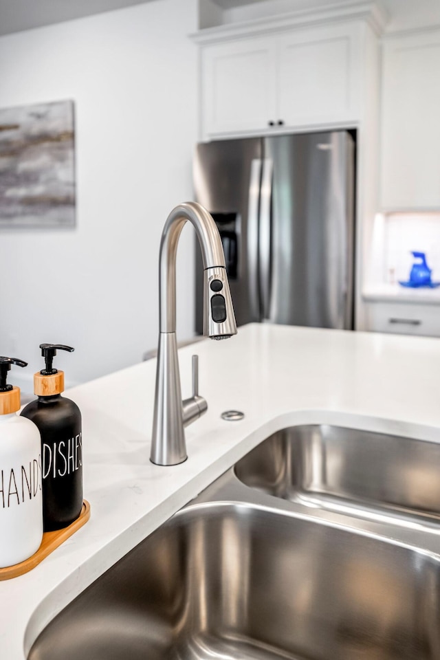 4786 E Whitman Rd, Springfield, MO 65802 - detailed view of stainless steel fridge with ice dispenser, a sink, and white cabinetry