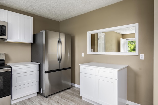2800 State Highway Bb, Hollister, MO 65672 - kitchen featuring stainless steel appliances, light countertops, light wood-style flooring, white cabinets, and a textured ceiling