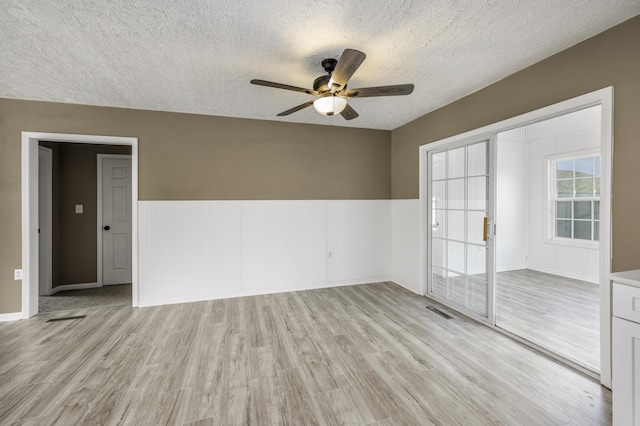 2800 State Highway Bb, Hollister, MO 65672 - empty room with a textured ceiling, ceiling fan, light wood-type flooring, and a wainscoted wall