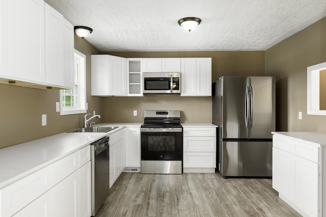 2800 State Highway Bb, Hollister, MO 65672 - kitchen with stainless steel appliances, a sink, a textured ceiling, light wood finished floors, and open shelves