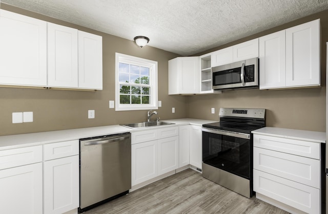 2800 State Highway Bb, Hollister, MO 65672 - kitchen featuring appliances with stainless steel finishes, a sink, open shelves, light wood-type flooring, and white cabinetry