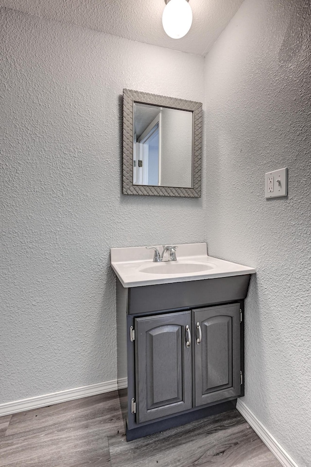 511 N E, Columbus, KS 66725 - bathroom with wood finished floors, vanity, baseboards, and a textured wall