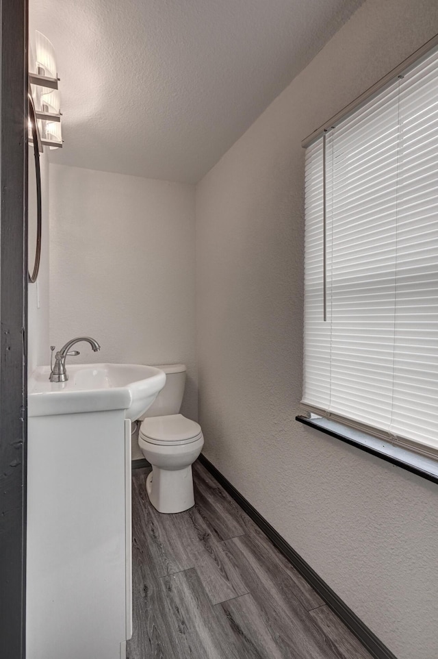 511 N E, Columbus, KS 66725 - bathroom featuring toilet, wood finished floors, vanity, a textured ceiling, and baseboards