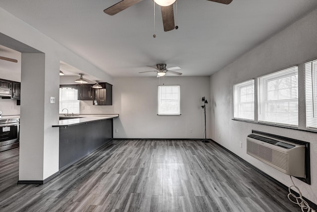 511 N E, Columbus, KS 66725 - unfurnished living room featuring ceiling fan, a wall mounted air conditioner, wood finished floors, and a sink