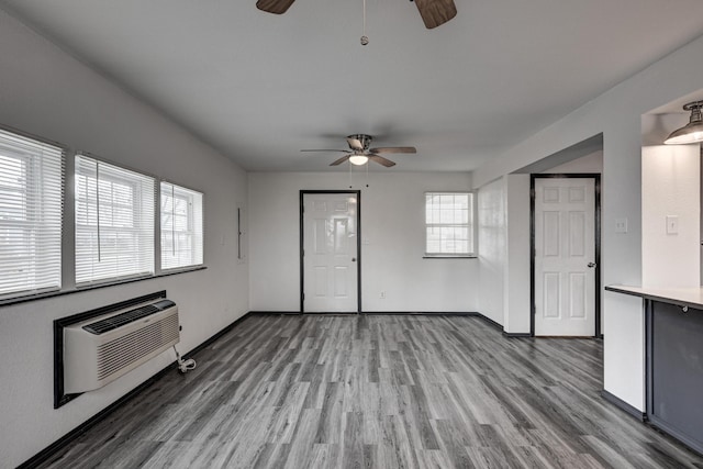 511 N E, Columbus, KS 66725 - unfurnished living room featuring a ceiling fan, wood finished floors, a wall mounted AC, and baseboards