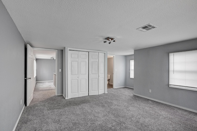 511 N E, Columbus, KS 66725 - unfurnished bedroom with a textured ceiling, carpet flooring, a closet, and baseboards