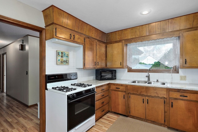 940 Carl Allen St, Mount Vernon, MO 65712 - kitchen with white range with gas stovetop, a sink, black microwave, light countertops, and decorative backsplash
